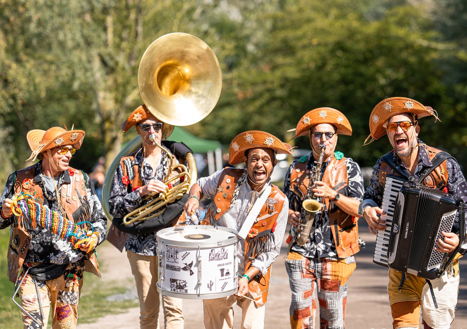 Fanfare Voa Voa en parade — musiciens en chapeaux de cangaceiro, sous le soleil